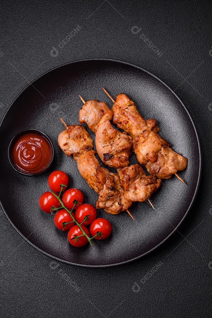 Delicioso frango fresco e suculento ou kebab de porco em espetos com sal e especiarias sobre um fundo escuro de concreto