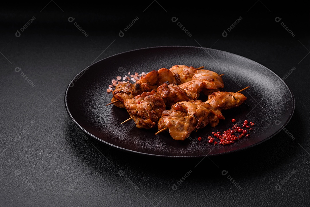 Delicioso frango fresco e suculento ou kebab de porco em espetos com sal e especiarias sobre um fundo escuro de concreto