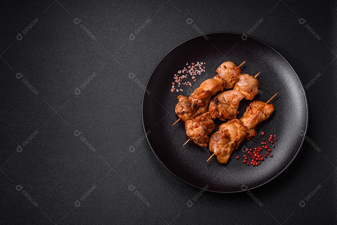 Delicioso frango fresco e suculento ou kebab de porco em espetos com sal e especiarias sobre um fundo escuro de concreto