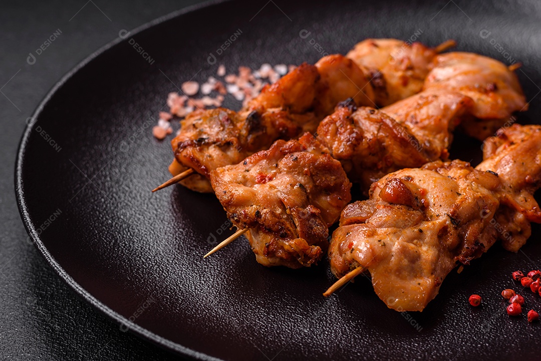 Delicioso frango fresco e suculento ou kebab de porco em espetos com sal e especiarias sobre um fundo escuro de concreto
