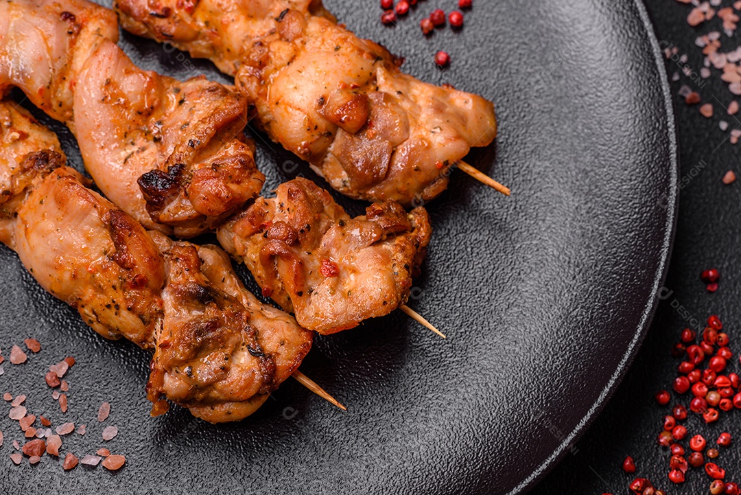 Delicioso frango fresco e suculento ou kebab de porco em espetos com sal e especiarias sobre um fundo escuro de concreto