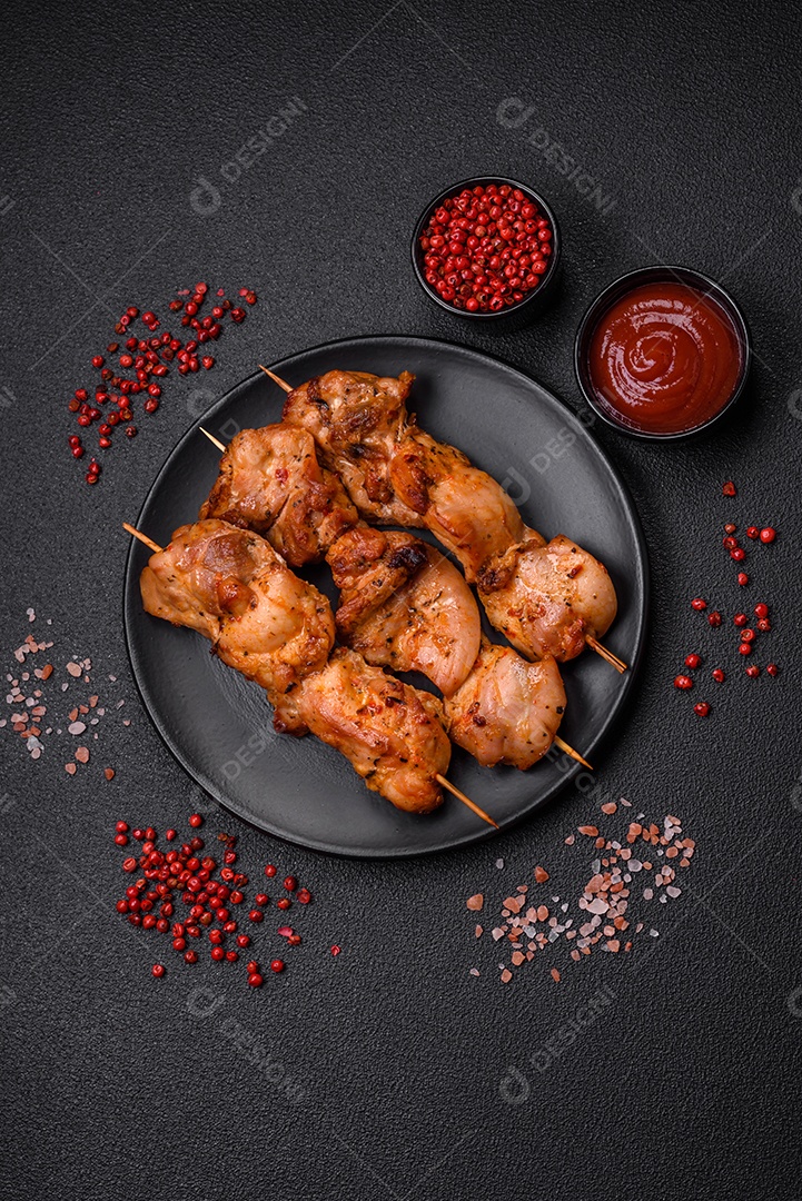 Delicioso frango fresco e suculento ou kebab de porco em espetos com sal e especiarias sobre um fundo escuro de concreto
