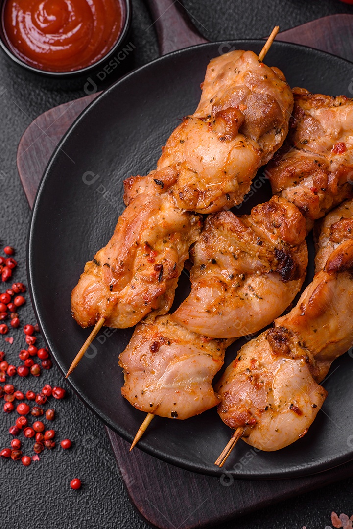 Delicioso frango fresco e suculento ou kebab de porco em espetos com sal e especiarias sobre um fundo escuro de concreto