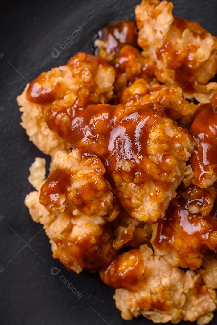 Deliciosas mordidas suculentas de carne de frango grelhado com sal, especiarias e ervas em um fundo escuro de concreto