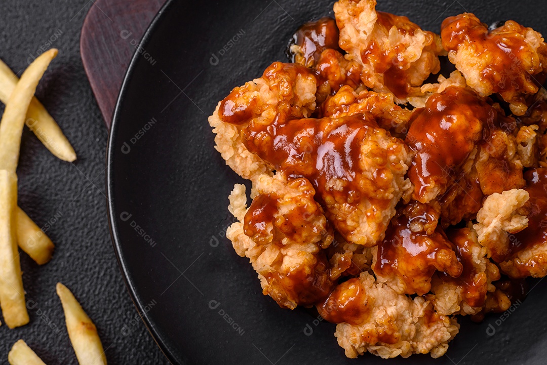 Deliciosas mordidas suculentas de carne de frango grelhado com sal, especiarias e ervas em um fundo escuro de concreto