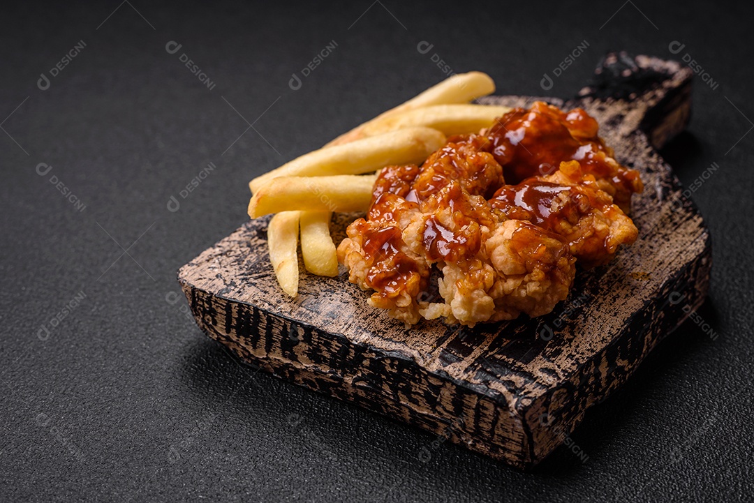 Deliciosas mordidas suculentas de carne de frango grelhado com sal, especiarias e ervas em um fundo escuro de concreto