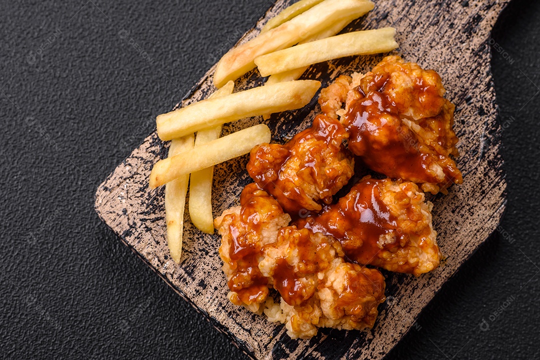 Deliciosas mordidas suculentas de carne de frango grelhado com sal, especiarias e ervas em um fundo escuro de concreto