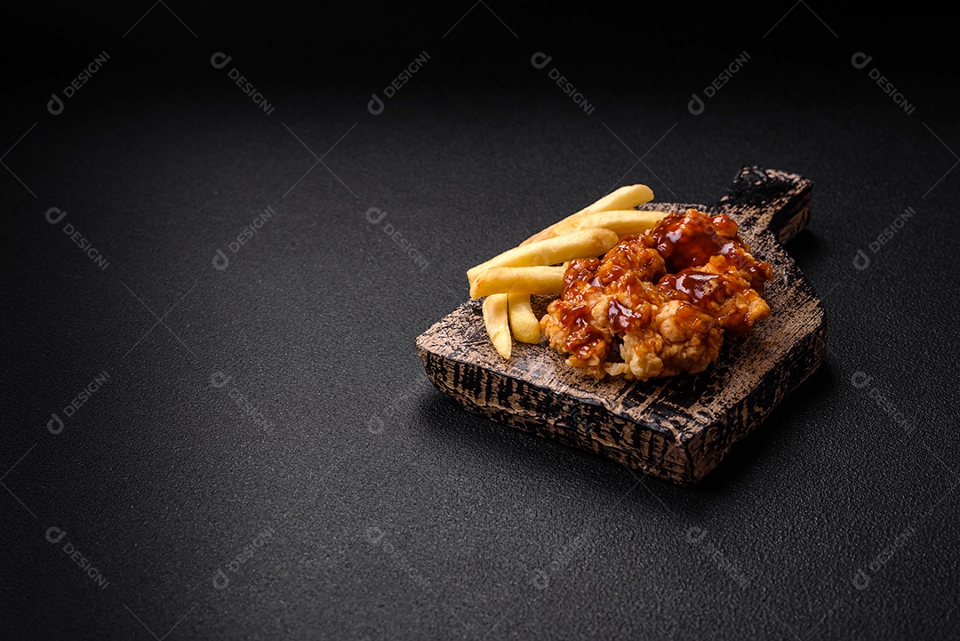 Deliciosas mordidas suculentas de carne de frango grelhado com sal, especiarias e ervas em um fundo escuro de concreto