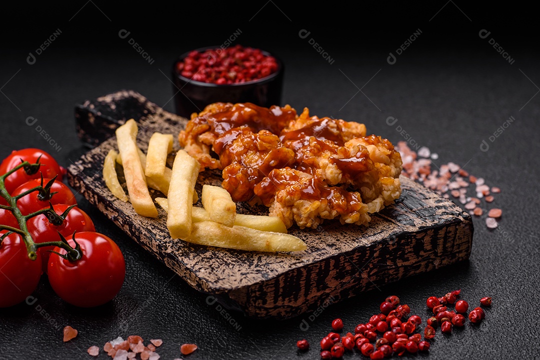 Deliciosas mordidas suculentas de carne de frango grelhado com sal, especiarias e ervas em um fundo escuro de concreto