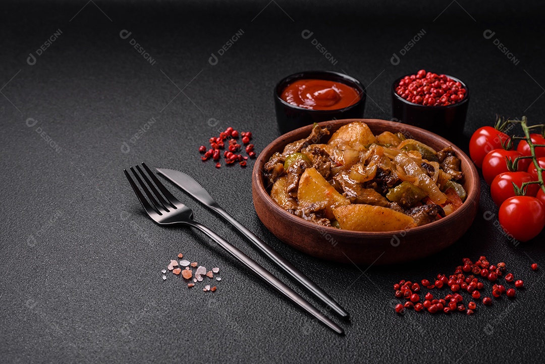 Delicioso guisado fresco de batatas, tomates, cebolas, cenouras e carne bovina com sal, especiarias e ervas sobre um fundo escuro de concreto