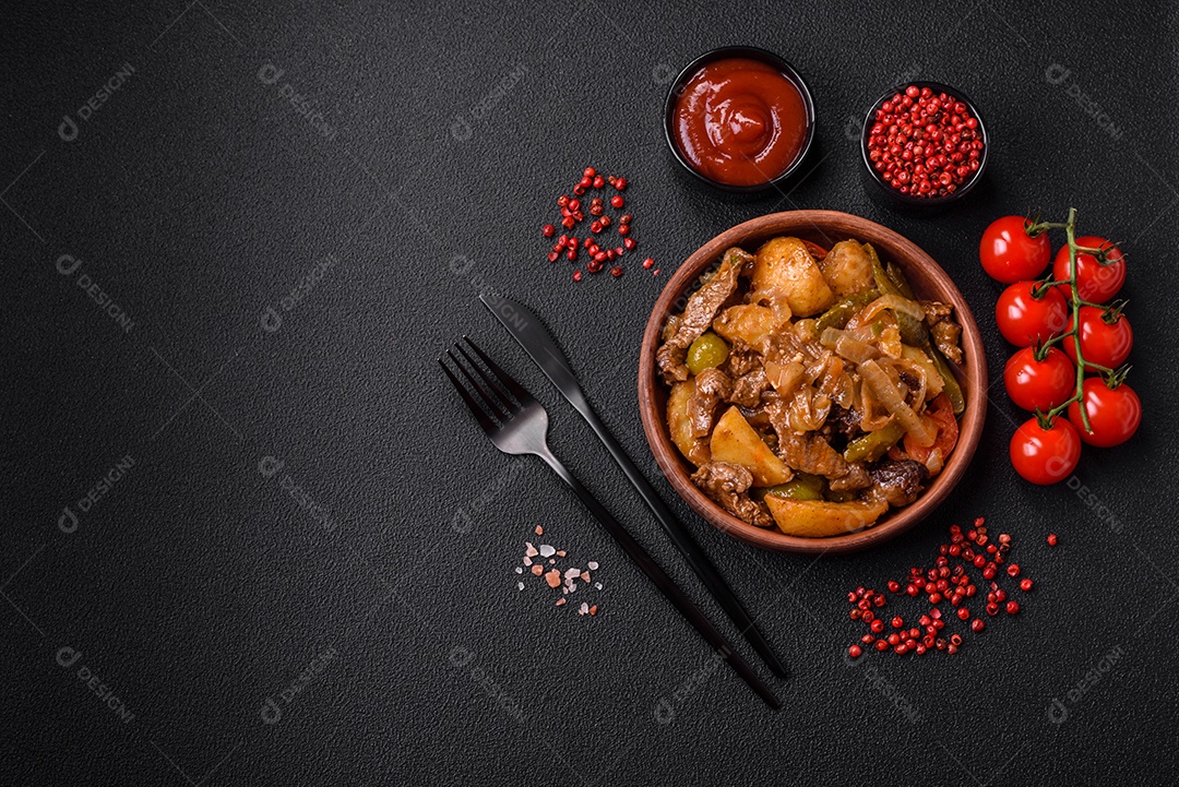 Delicioso guisado fresco de batatas, tomates, cebolas, cenouras e carne bovina com sal, especiarias e ervas sobre um fundo escuro de concreto