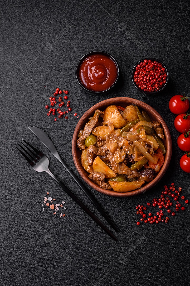Delicioso guisado fresco de batatas, tomates, cebolas, cenouras e carne bovina com sal, especiarias e ervas sobre um fundo escuro de concreto