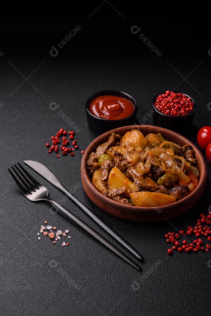 Delicioso guisado fresco de batatas, tomates, cebolas, cenouras e carne bovina com sal, especiarias e ervas sobre um fundo escuro de concreto