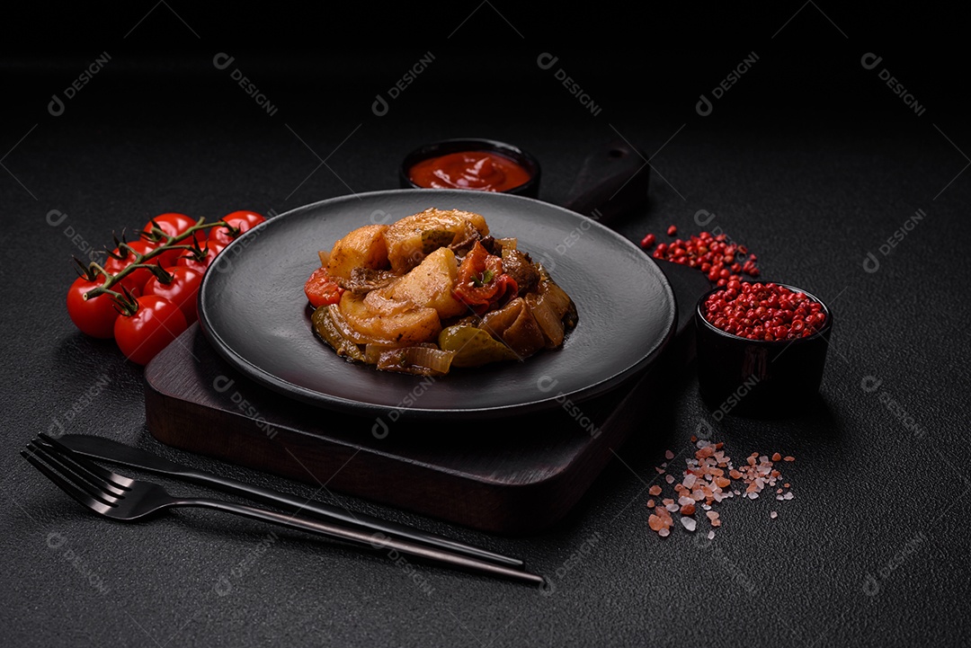 Delicioso guisado fresco de batatas, tomates, cebolas, cenouras e carne bovina com sal, especiarias e ervas sobre um fundo escuro de concreto