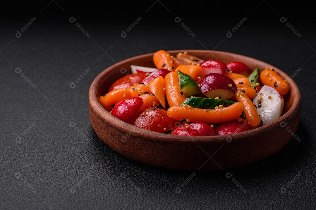 Deliciosa salada fresca e suculenta com rabanetes, tomates, cenouras, pepino, especiarias e ervas sobre um fundo escuro de concreto