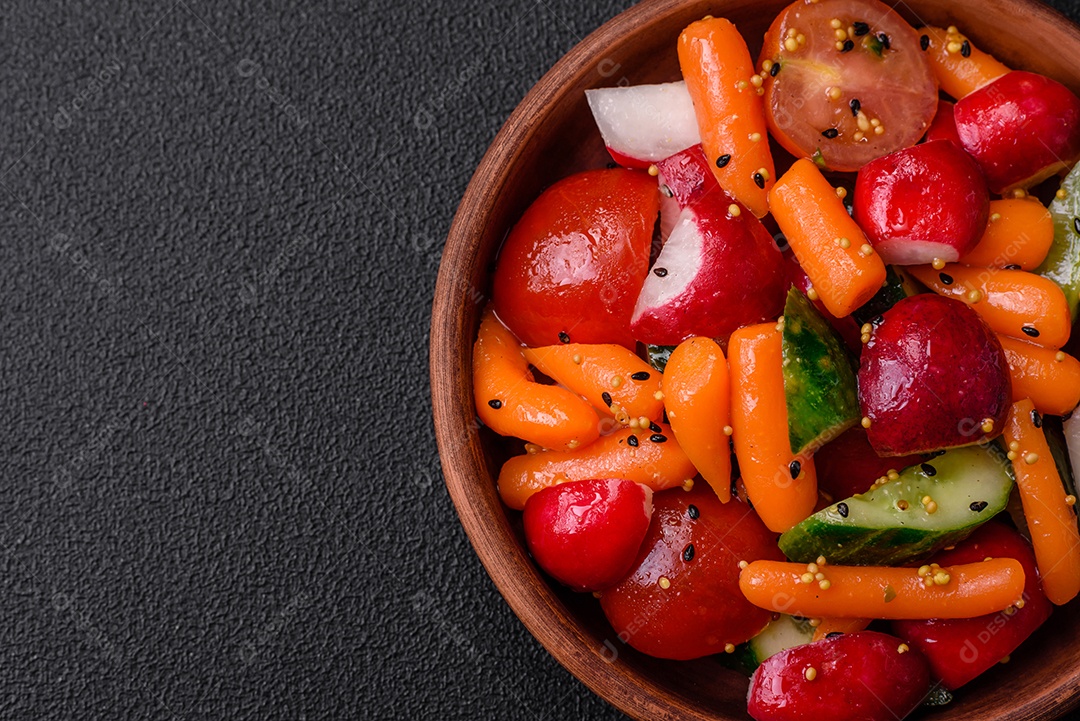 Deliciosa salada fresca e suculenta com rabanetes, tomates, cenouras, pepino, especiarias e ervas sobre um fundo escuro de concreto