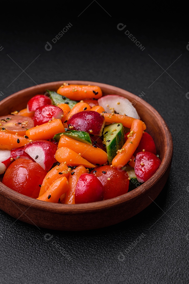 Deliciosa salada fresca e suculenta com rabanetes, tomates, cenouras, pepino, especiarias e ervas sobre um fundo escuro de concreto