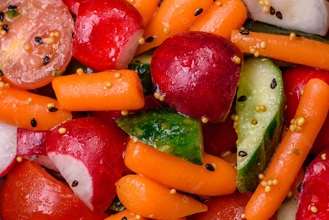 Deliciosa salada fresca e suculenta com rabanetes, tomates, cenouras, pepino, especiarias e ervas sobre um fundo escuro de concreto