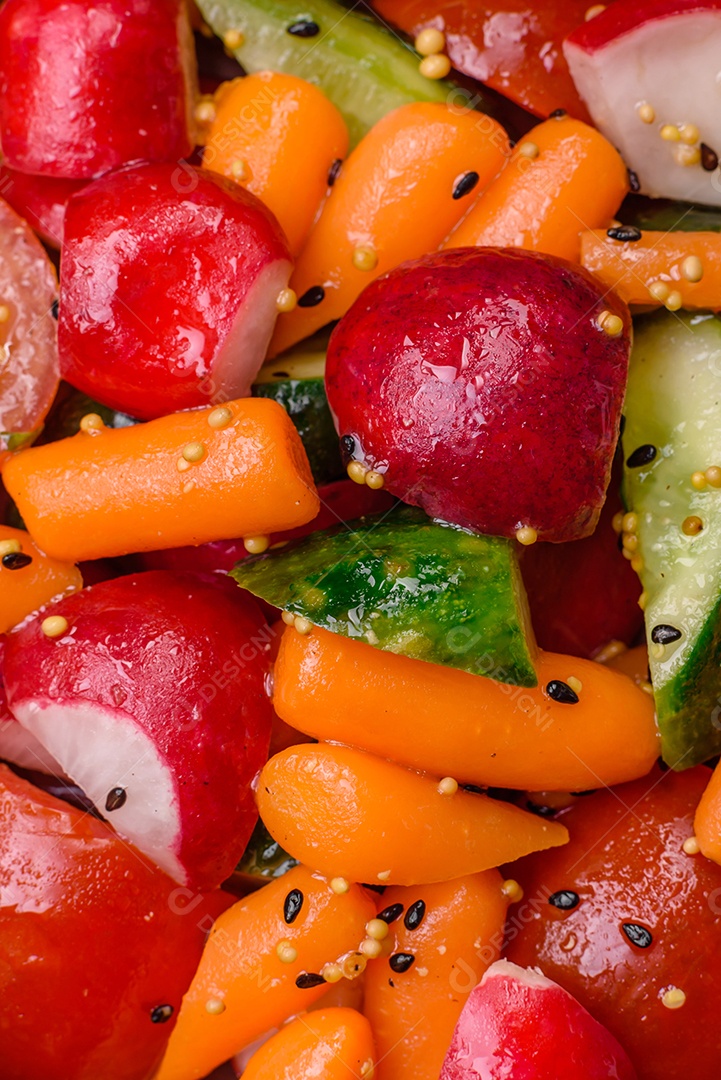 Deliciosa salada fresca e suculenta com rabanetes, tomates, cenouras, pepino, especiarias e ervas sobre um fundo escuro de concreto