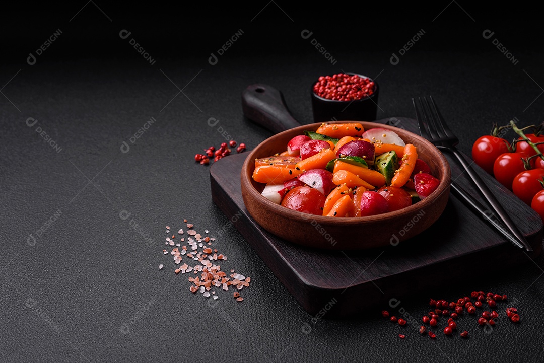 Deliciosa salada fresca e suculenta com rabanetes, tomates, cenouras, pepino, especiarias e ervas sobre um fundo escuro de concreto