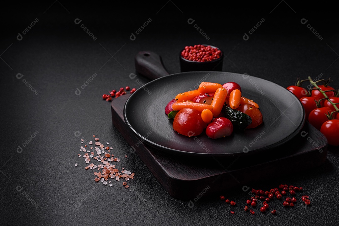 Deliciosa salada fresca e suculenta com rabanetes, tomates, cenouras, pepino, especiarias e ervas sobre um fundo escuro de concreto