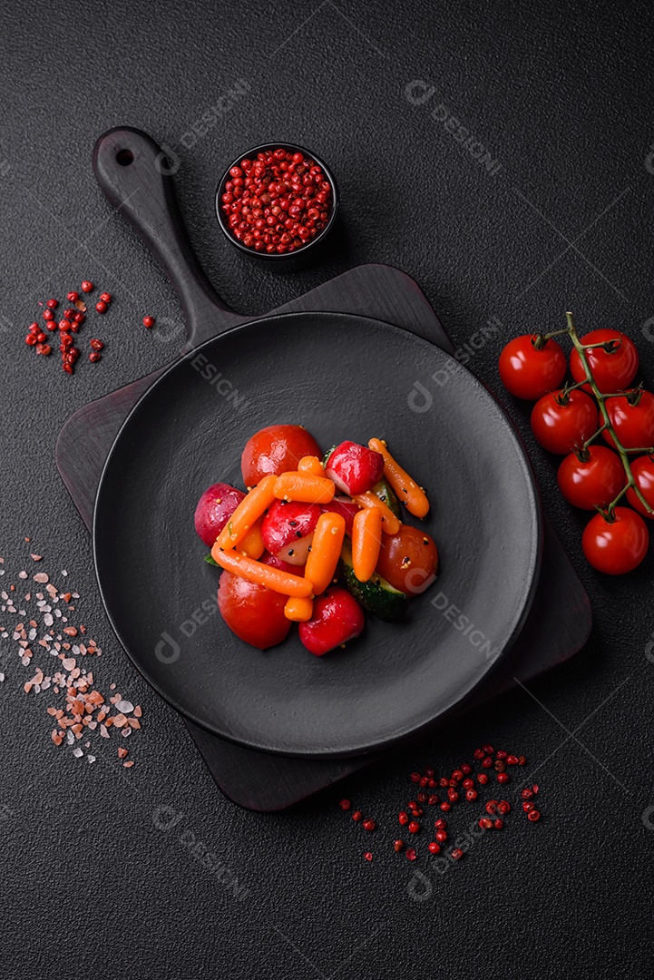 Deliciosa salada fresca e suculenta com rabanetes, tomates, cenouras, pepino, especiarias e ervas sobre um fundo escuro de concreto