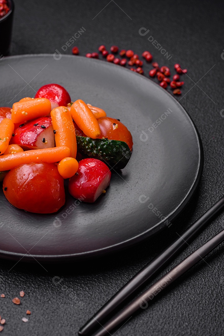 Deliciosa salada fresca e suculenta com rabanetes, tomates, cenouras, pepino, especiarias e ervas sobre um fundo escuro de concreto