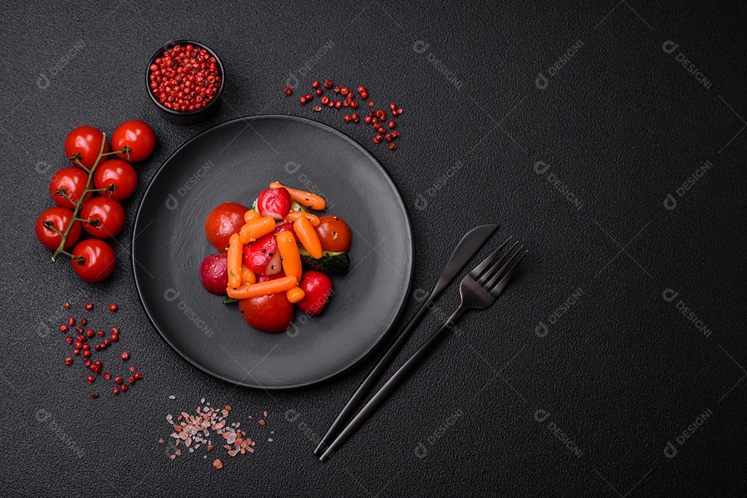 Deliciosa salada fresca e suculenta com rabanetes, tomates, cenouras, pepino, especiarias e ervas sobre um fundo escuro de concreto