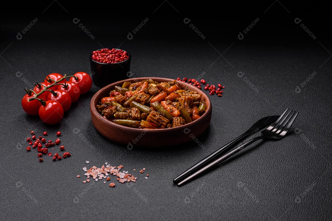 Mistura de legumes, milho, cenoura, pimentão, brócolis, cebola em molho teriyaki em uma placa de cerâmica sobre um fundo escuro de concreto