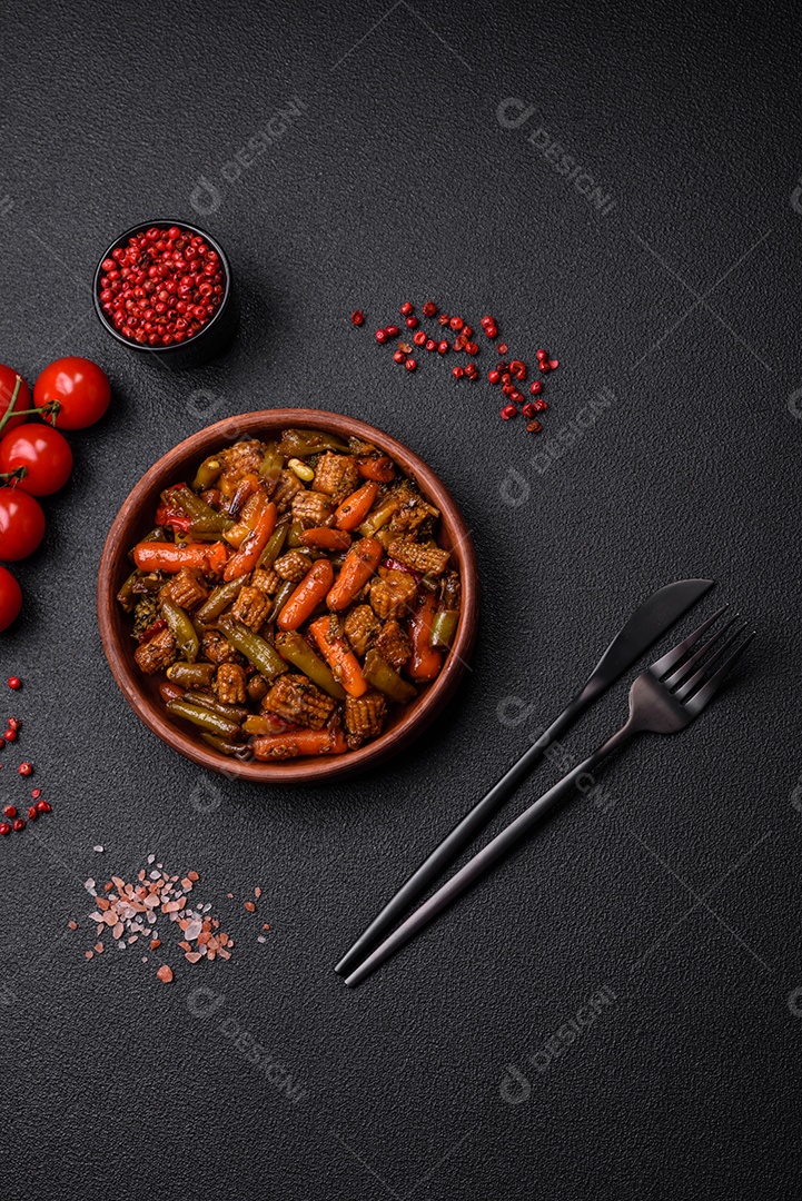 Mistura de legumes, milho, cenoura, pimentão, brócolis, cebola em molho teriyaki em uma placa de cerâmica sobre um fundo escuro de concreto