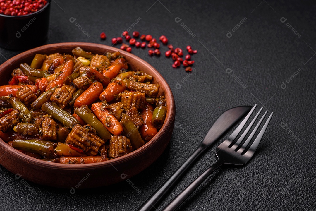 Mistura de legumes, milho, cenoura, pimentão, brócolis, cebola em molho teriyaki em uma placa de cerâmica sobre um fundo escuro de concreto