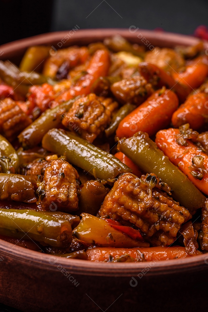 Mistura de legumes, milho, cenoura, pimentão, brócolis, cebola em molho teriyaki em uma placa de cerâmica sobre um fundo escuro de concreto