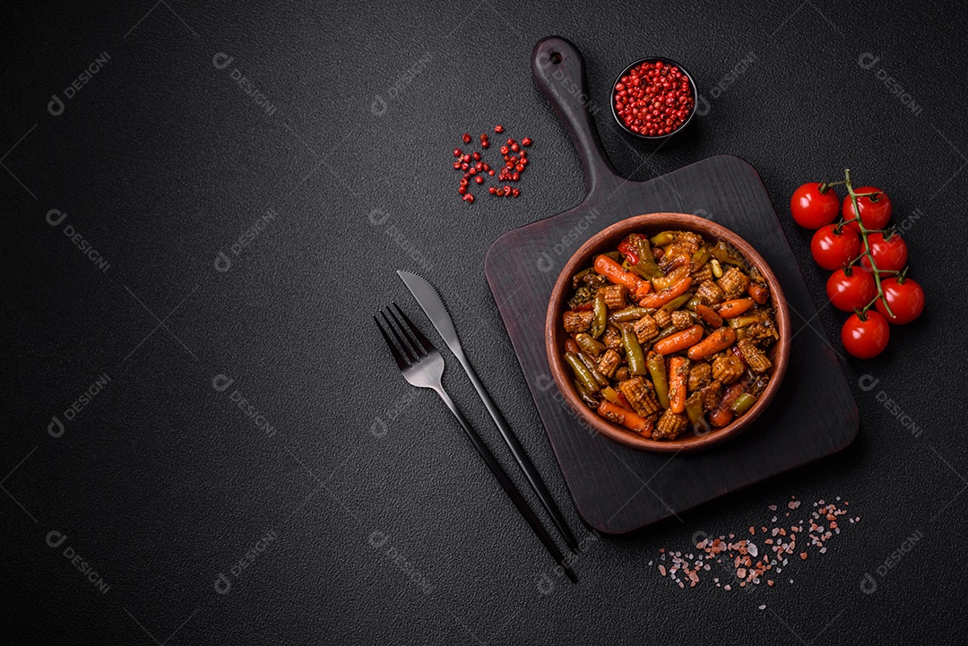 Mistura de legumes, milho, cenoura, pimentão, brócolis, cebola em molho teriyaki em uma placa de cerâmica sobre um fundo escuro de concreto