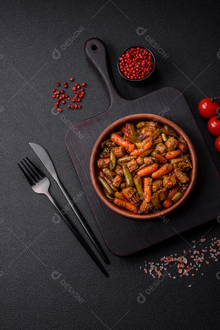 Mistura de legumes, milho, cenoura, pimentão, brócolis, cebola em molho teriyaki em uma placa de cerâmica sobre um fundo escuro de concreto
