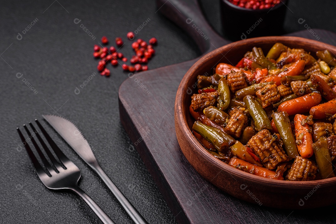 Mistura de legumes, milho, cenoura, pimentão, brócolis, cebola em molho teriyaki em uma placa de cerâmica sobre um fundo escuro de concreto