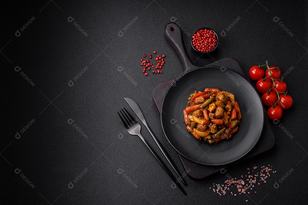 Mistura de legumes, milho, cenoura, pimentão, brócolis, cebola em molho teriyaki em uma placa de cerâmica sobre um fundo escuro de concreto