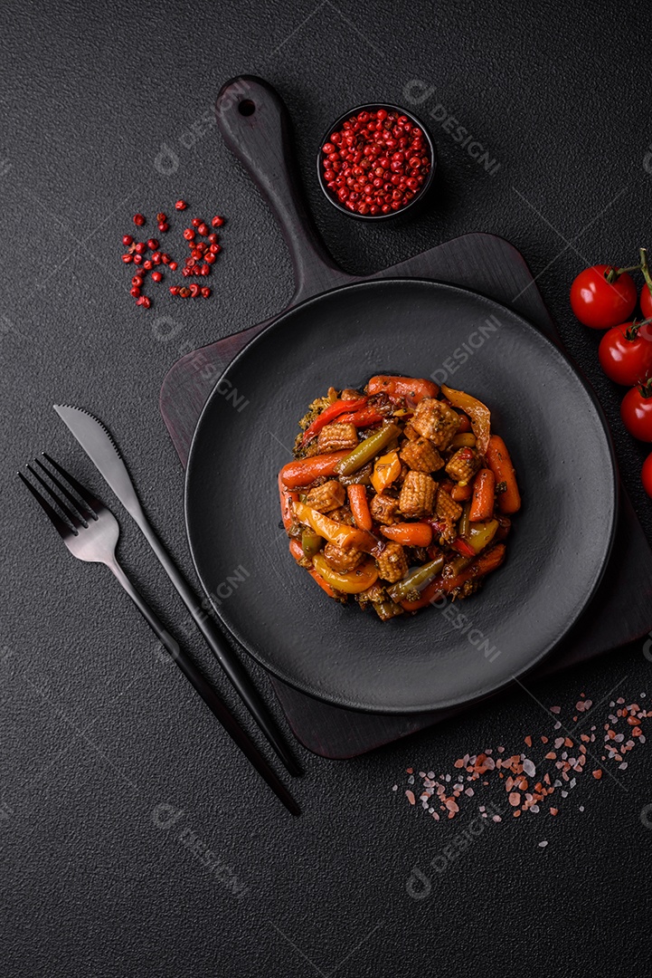Mistura de legumes, milho, cenoura, pimentão, brócolis, cebola em molho teriyaki em uma placa de cerâmica sobre um fundo escuro de concreto