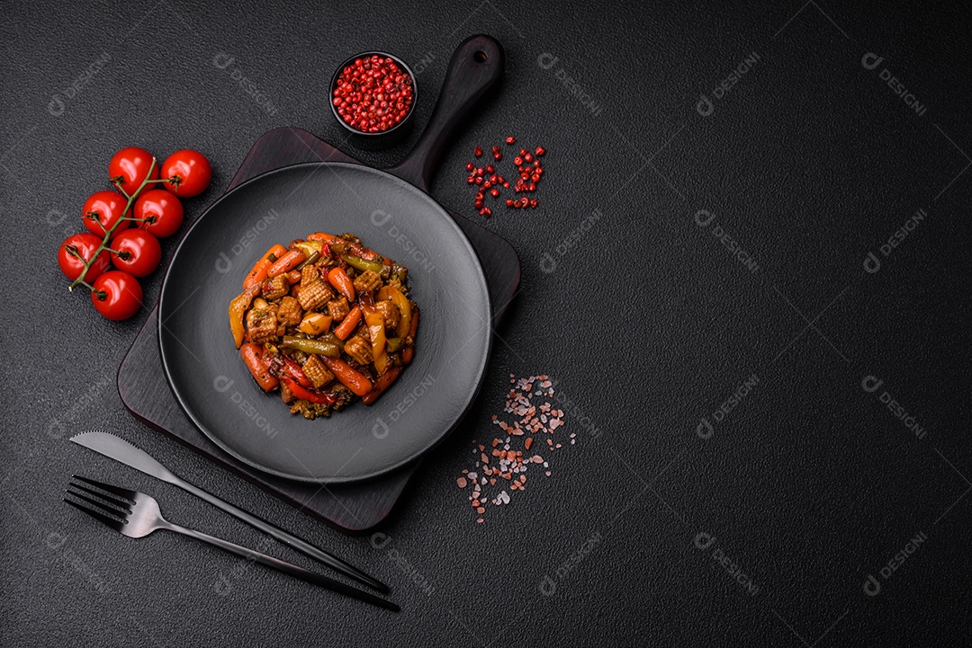 Mistura de legumes, milho, cenoura, pimentão, brócolis, cebola em molho teriyaki em uma placa de cerâmica sobre um fundo escuro de concreto
