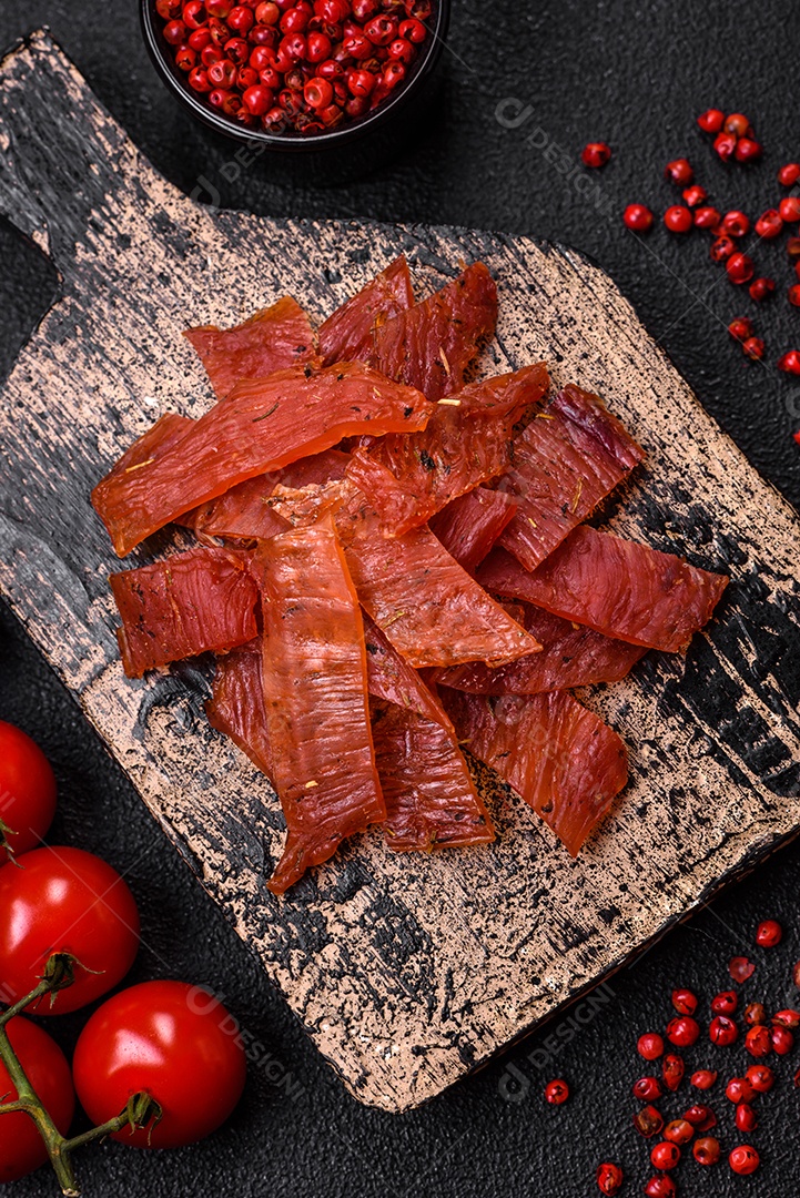 Deliciosa vitela seca ou carne seca de peru com sal, especiarias e ervas sobre um fundo escuro de concreto