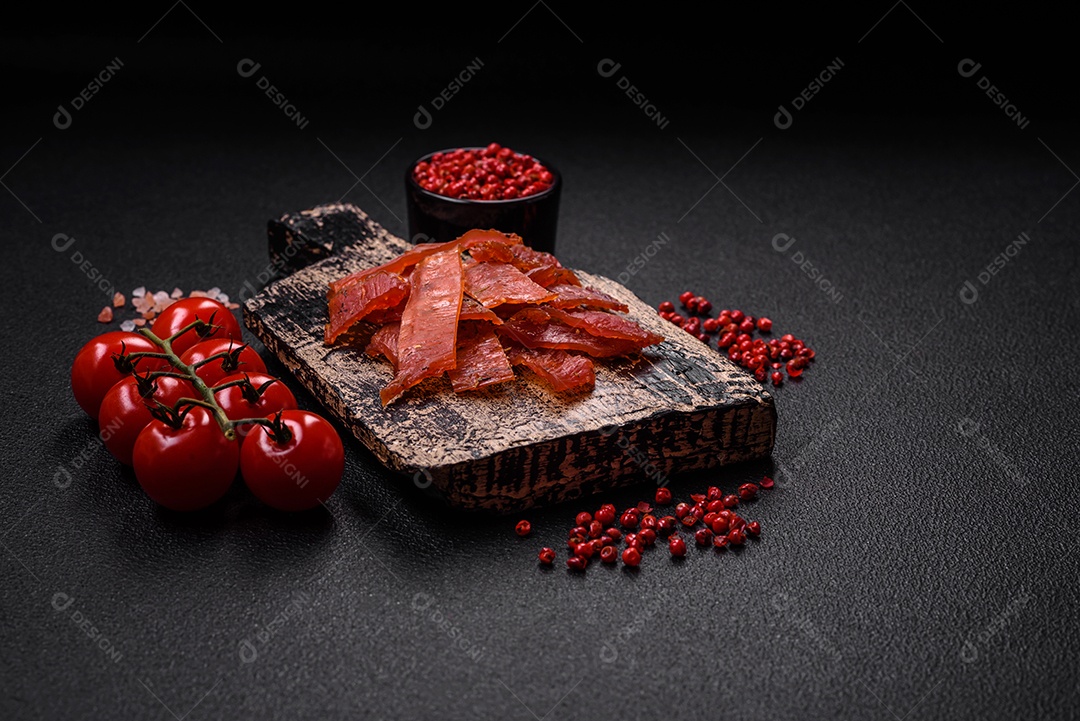 Deliciosa vitela seca ou carne seca de peru com sal, especiarias e ervas sobre um fundo escuro de concreto