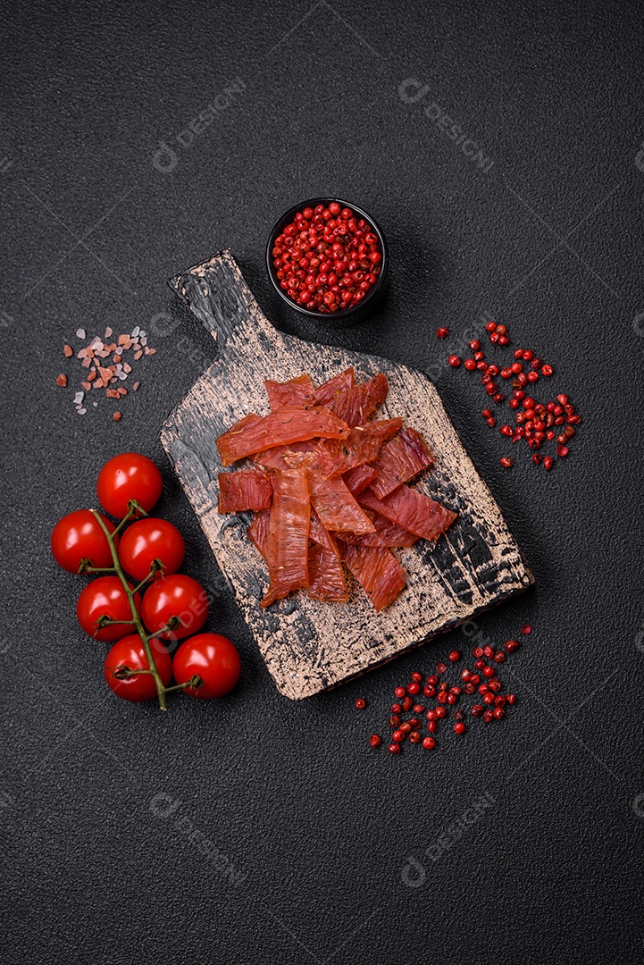 Deliciosa vitela seca ou carne seca de peru com sal, especiarias e ervas sobre um fundo escuro de concreto