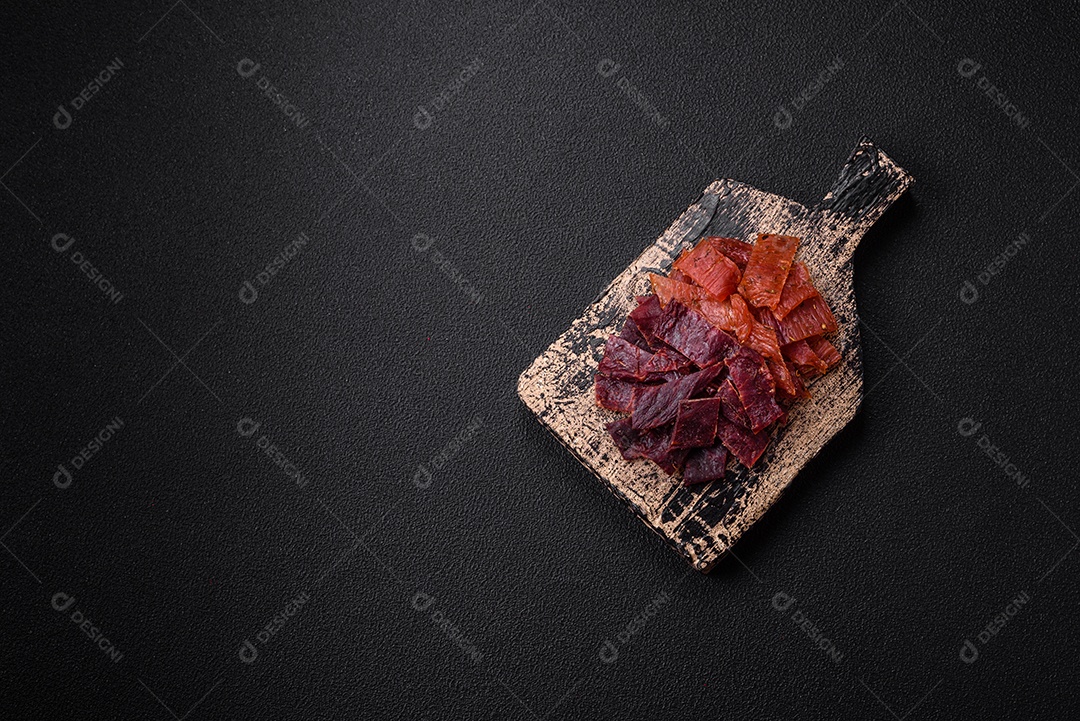 Deliciosa vitela seca ou carne seca de peru com sal, especiarias e ervas sobre um fundo escuro de concreto