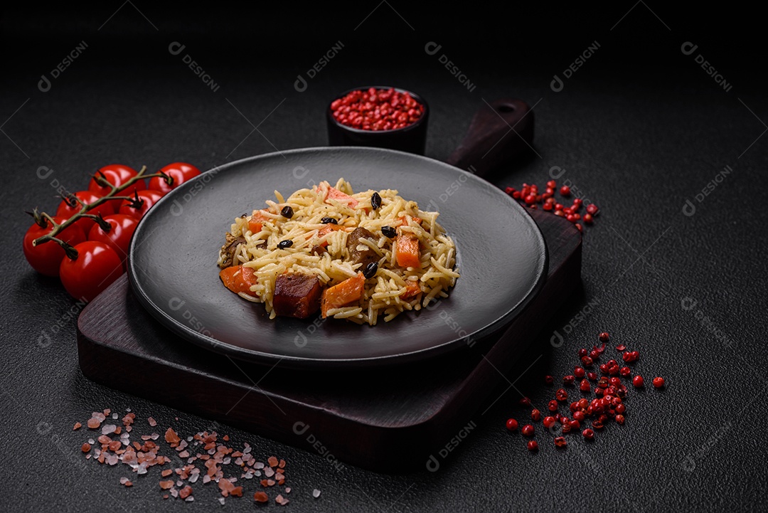 Delicioso pilaf uzbeque com frango, cenoura, bérberis, especiarias e ervas sobre um fundo escuro de concreto