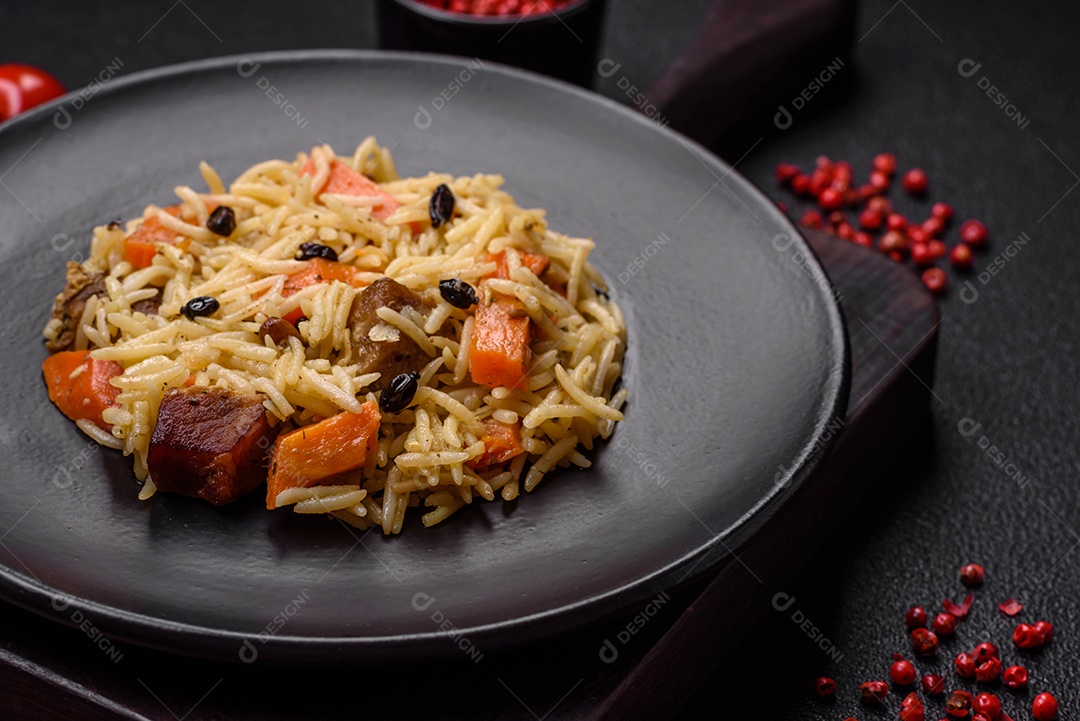Delicioso pilaf uzbeque com frango, cenoura, bérberis, especiarias e ervas sobre um fundo escuro de concreto