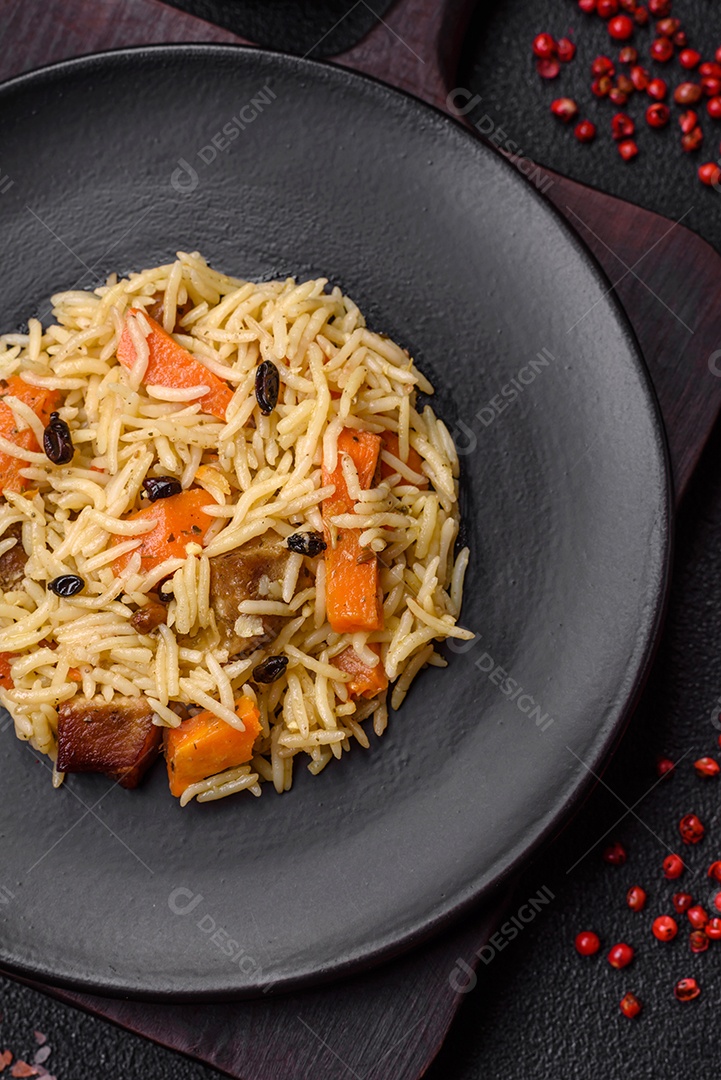 Delicioso pilaf uzbeque com frango, cenoura, bérberis, especiarias e ervas sobre um fundo escuro de concreto