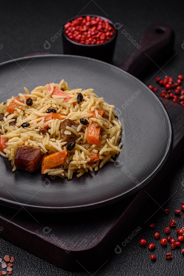 Delicioso pilaf uzbeque com frango, cenoura, bérberis, especiarias e ervas sobre um fundo escuro de concreto