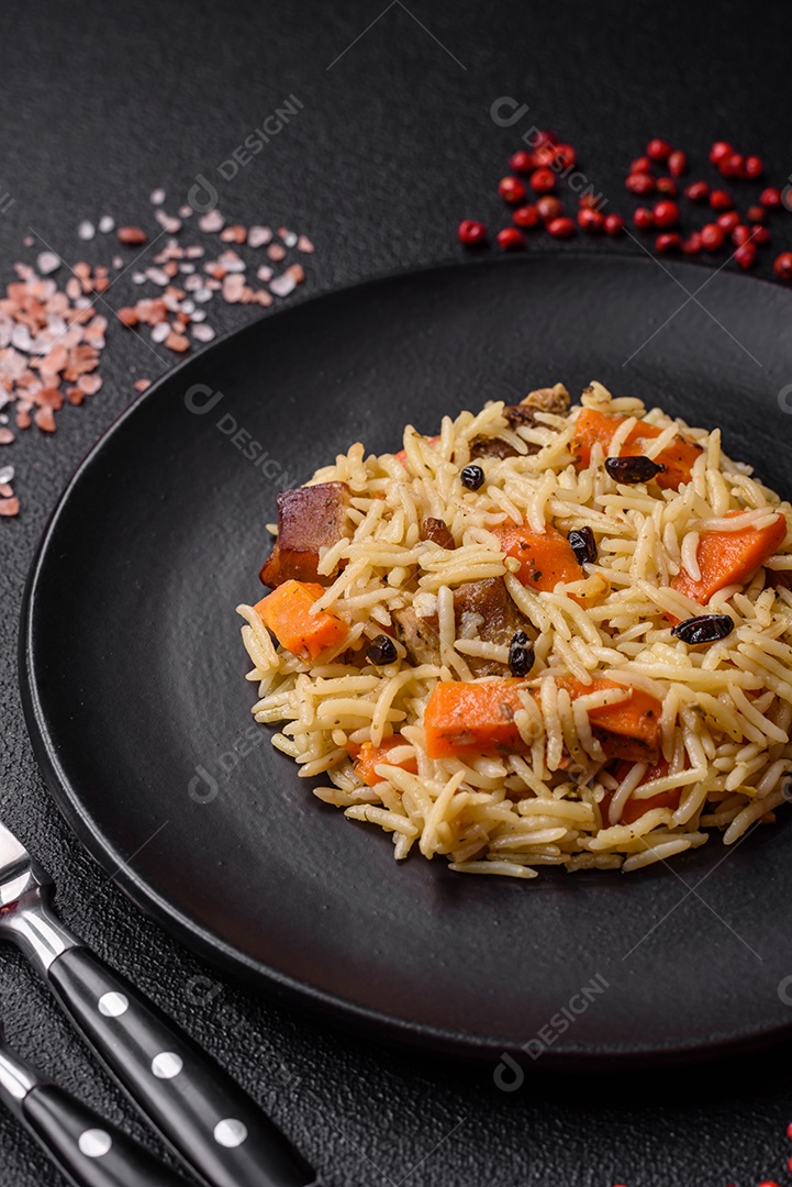 Delicioso pilaf uzbeque com frango, cenoura, bérberis, especiarias e ervas sobre um fundo escuro de concreto