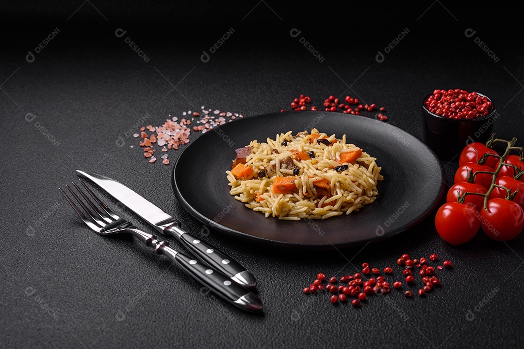 Delicioso pilaf uzbeque com frango, cenoura, bérberis, especiarias e ervas sobre um fundo escuro de concreto