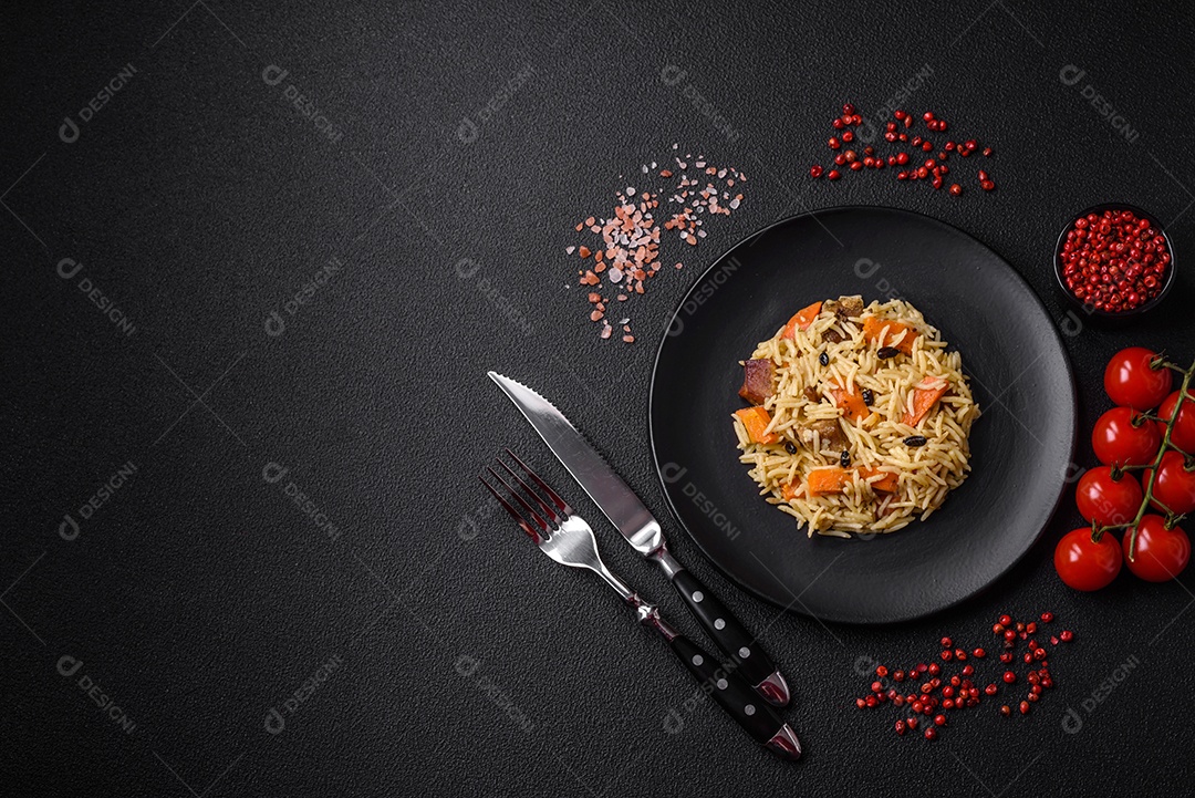Delicioso pilaf uzbeque com frango, cenoura, bérberis, especiarias e ervas sobre um fundo escuro de concreto