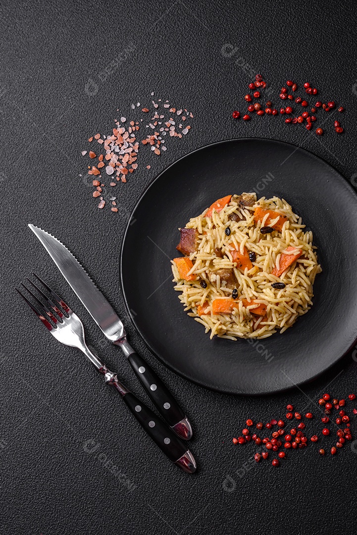 Delicioso pilaf uzbeque com frango, cenoura, bérberis, especiarias e ervas sobre um fundo escuro de concreto